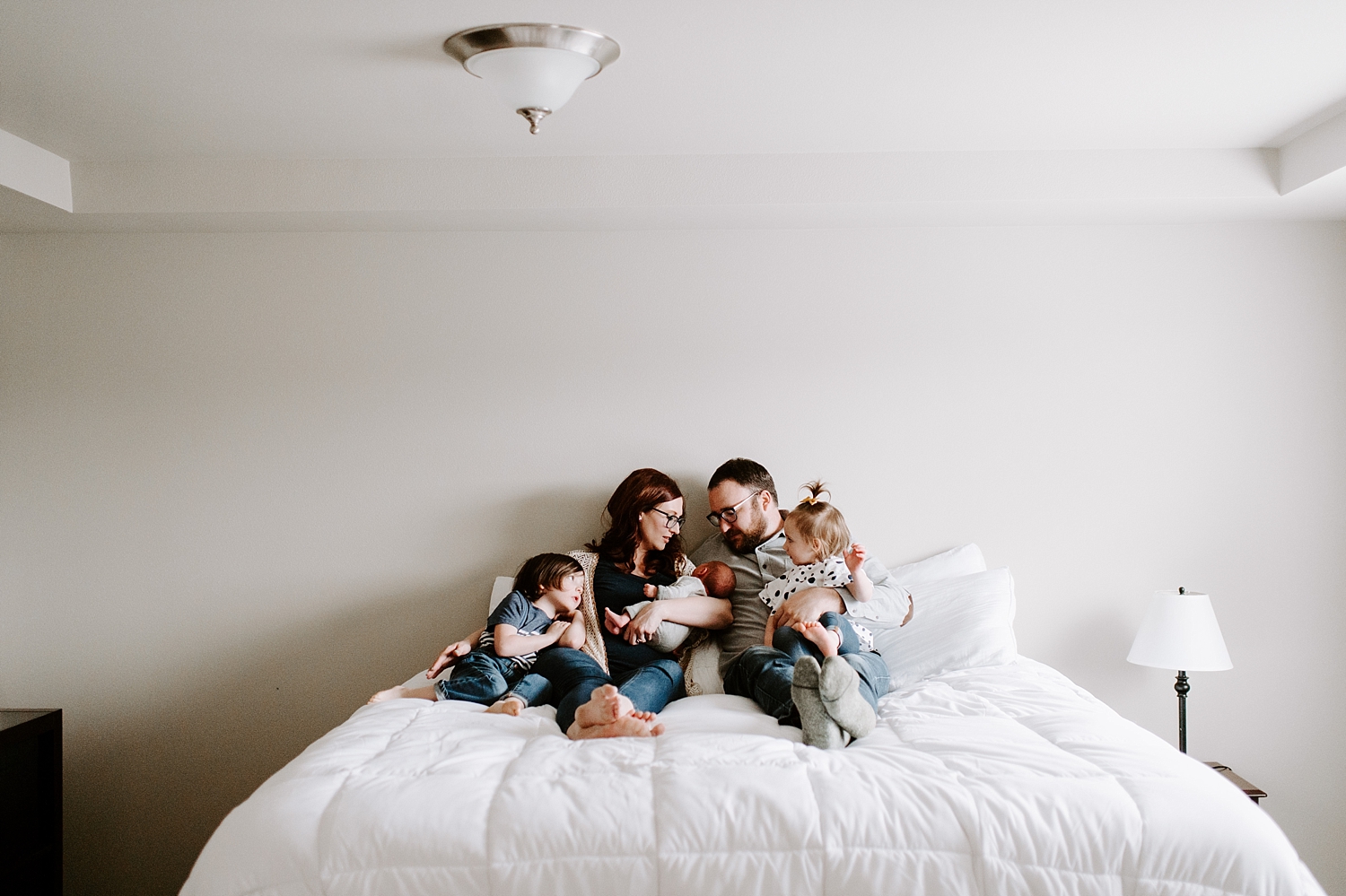 Family on bed together during lifestyle newborn session | Meg Newton Photography