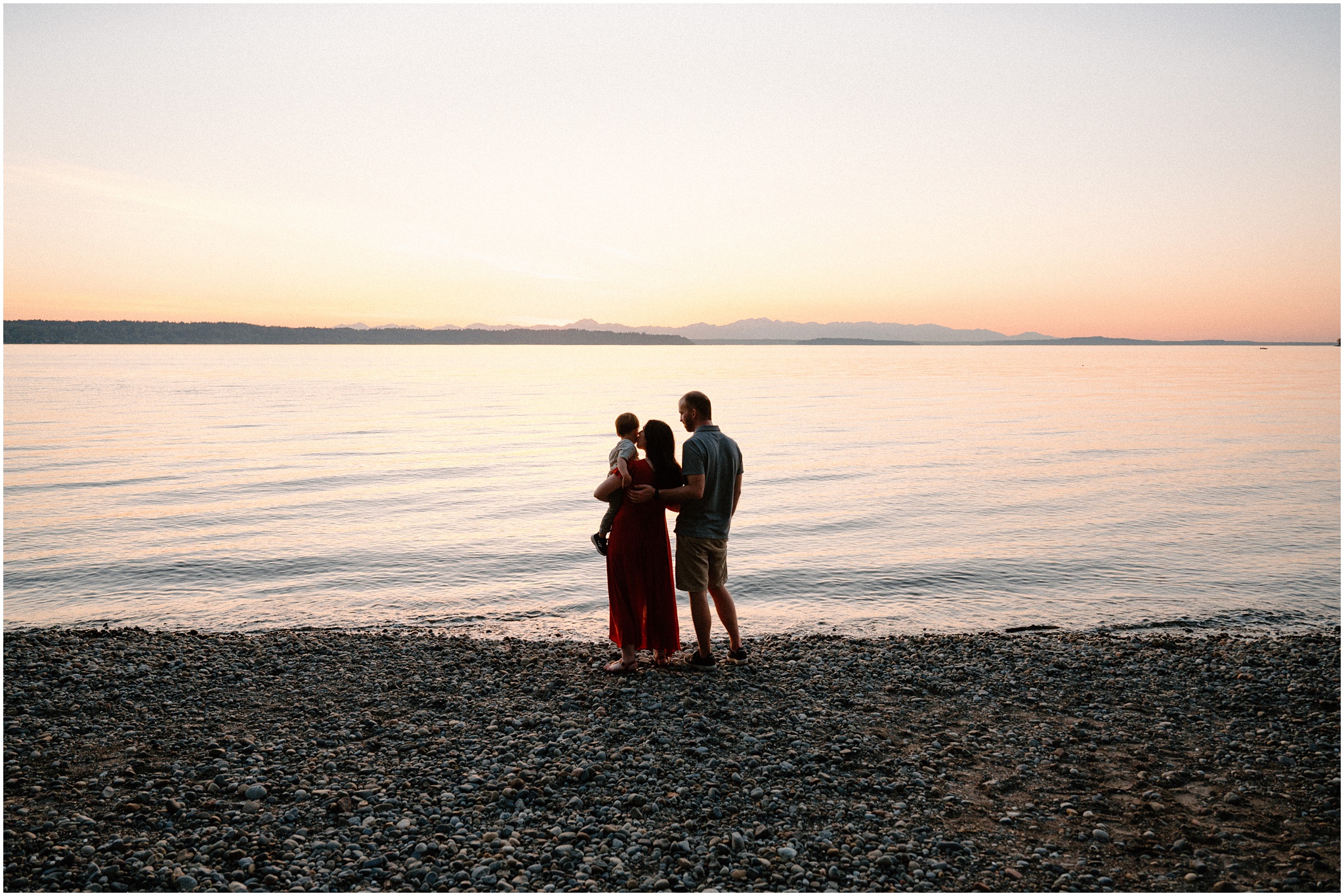 Family of three watches the sunset during their Tacoma maternity session. Photo by Meg Newton Photography.
