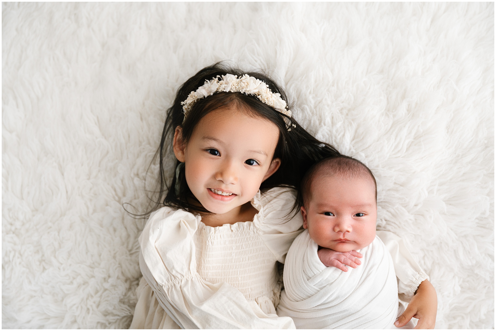Siblings pose during newborn studio session. Photo by Meg Newton Photography.