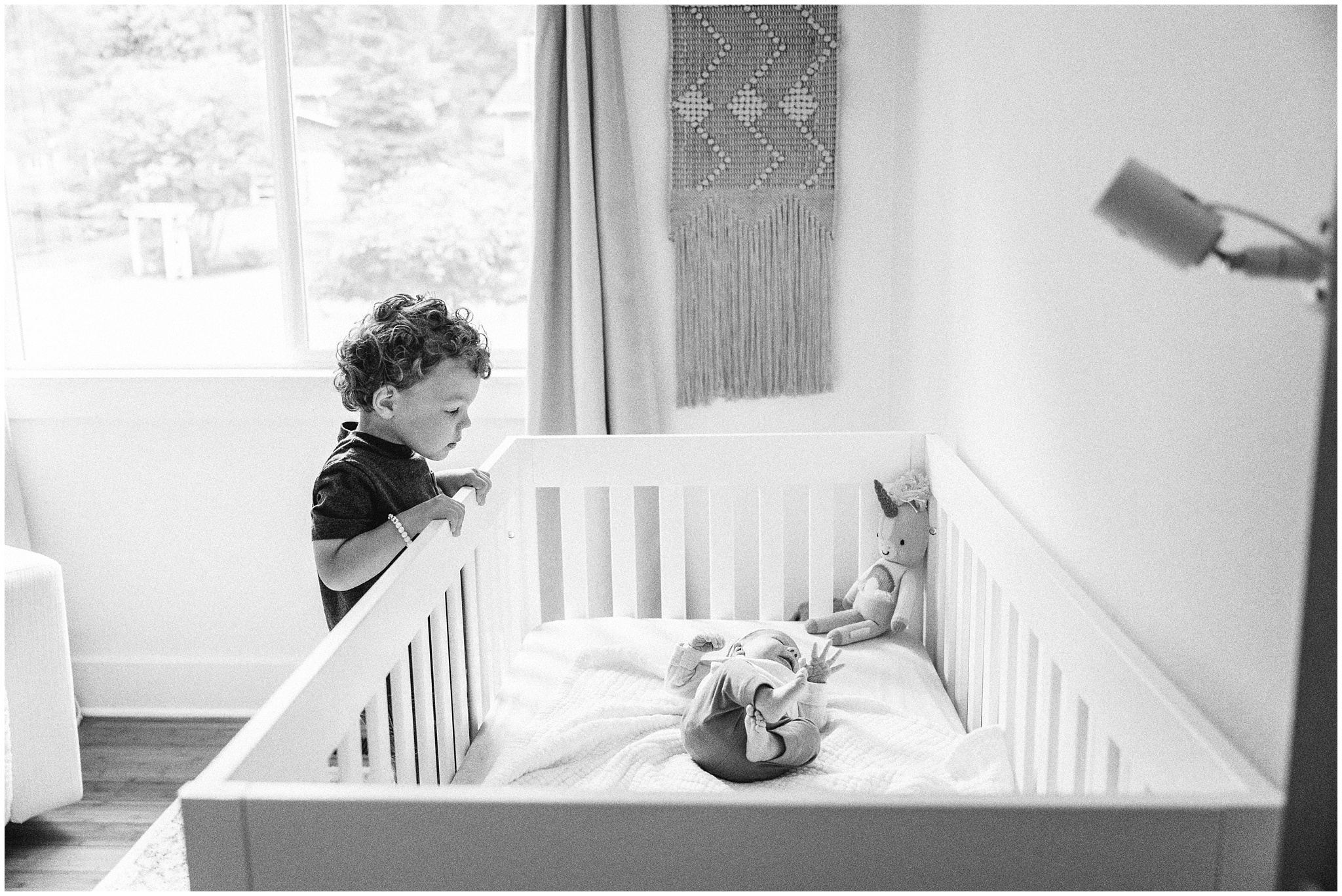 Big brother watches baby sister in crib during Woodinville newborn session. Photo by Meg Newton Photography.