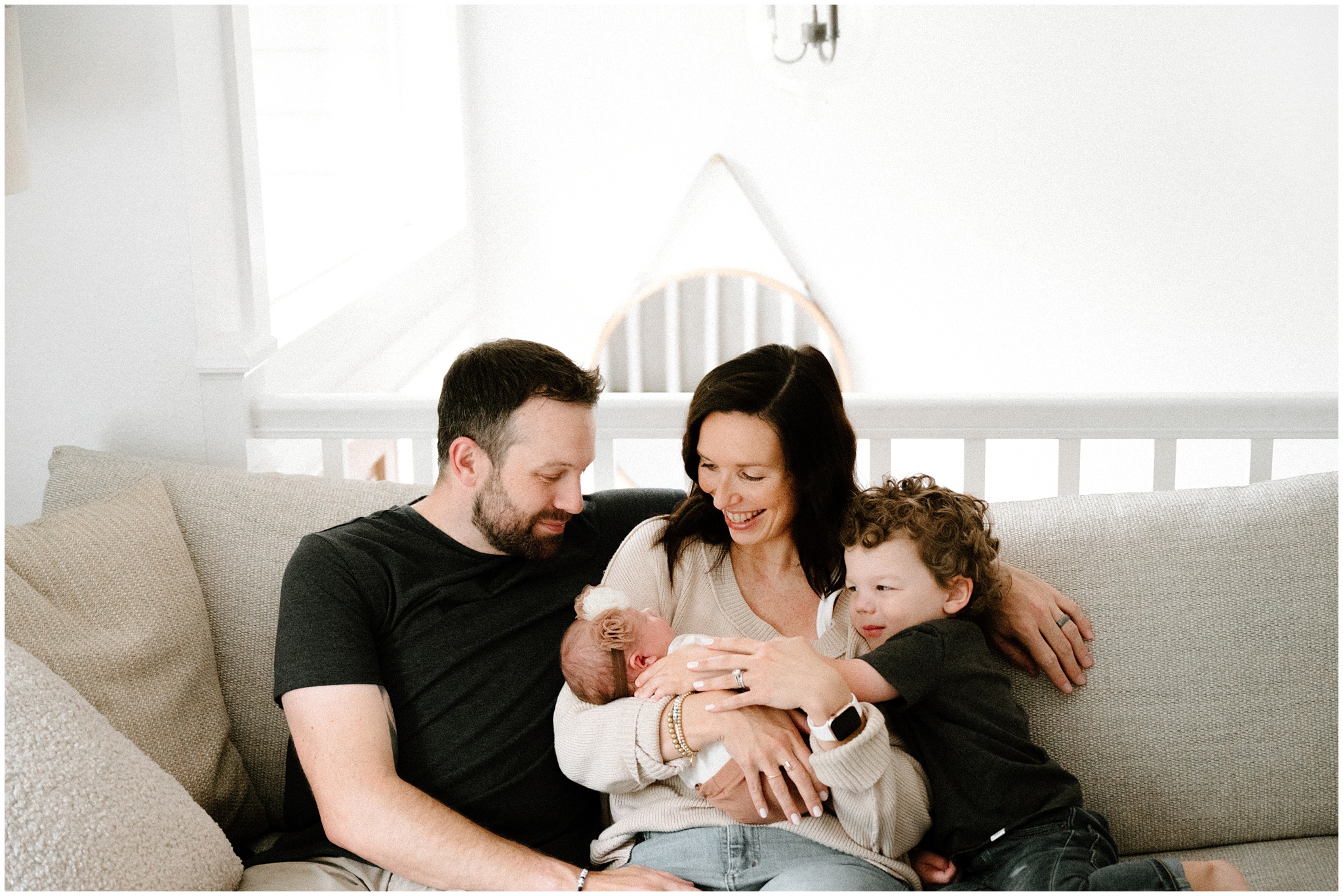 Family snuggles on couch with their newest family member. Photo by Meg Newton Photography.