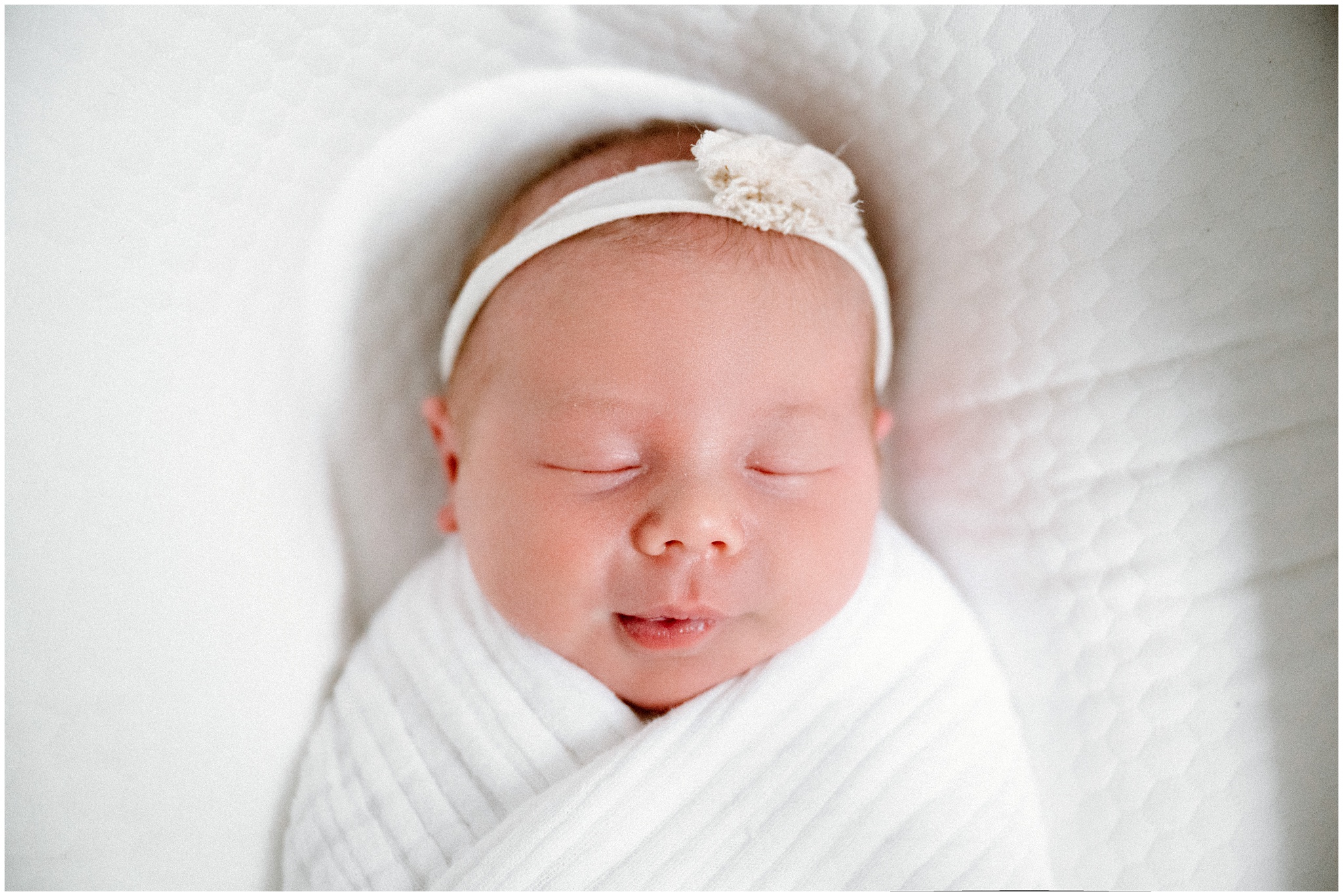 Baby girl wrapped in white swaddle. Photo by Meg Newton Photography.