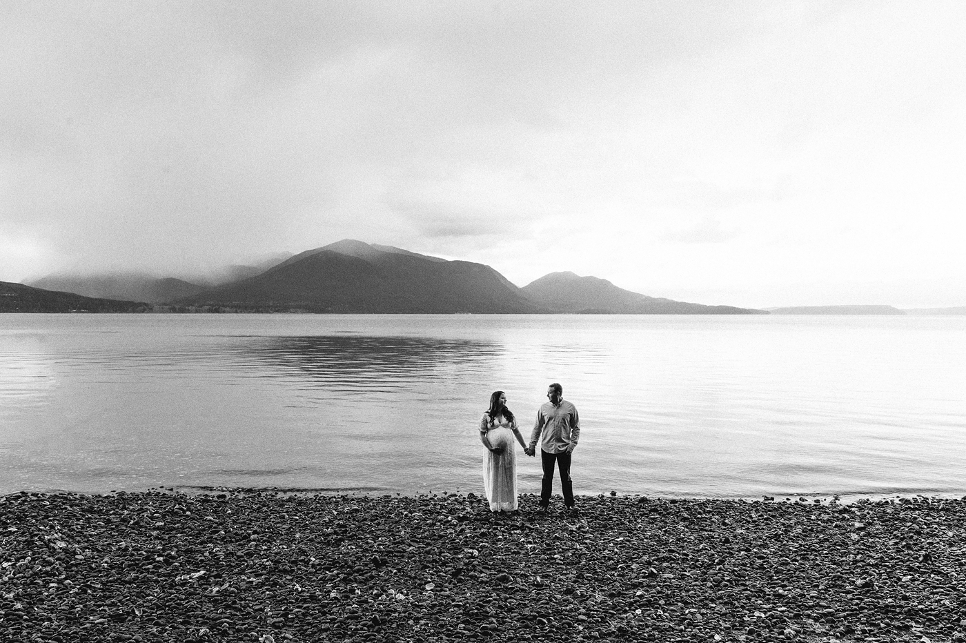 Landscape image of expecting parents in front of Hood Canal. Photo by Meg Newton Photography.
