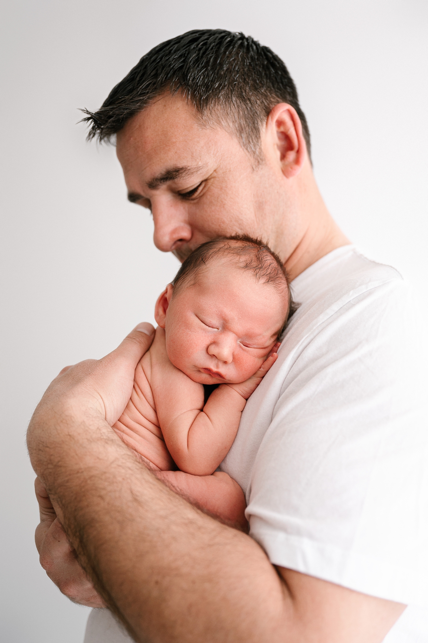 Dad cradles son at studio newborn session. Photo by Meg Newton Photography.
