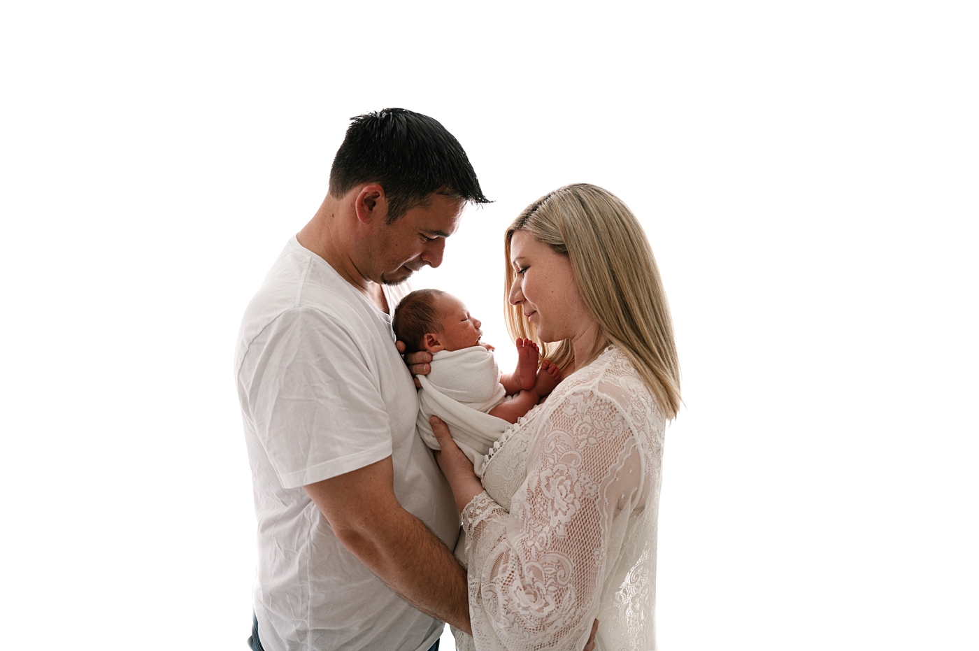 New parents hold child between them during newborn session. Photo by Meg Newton Photography.