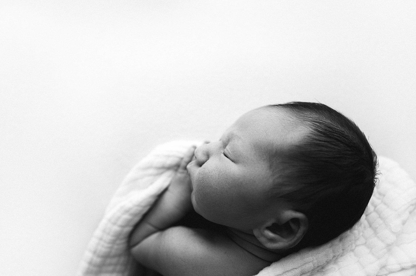 Sweet baby snuggles his swaddle during Tacoma studio session. Photo by Meg Newton Photography.