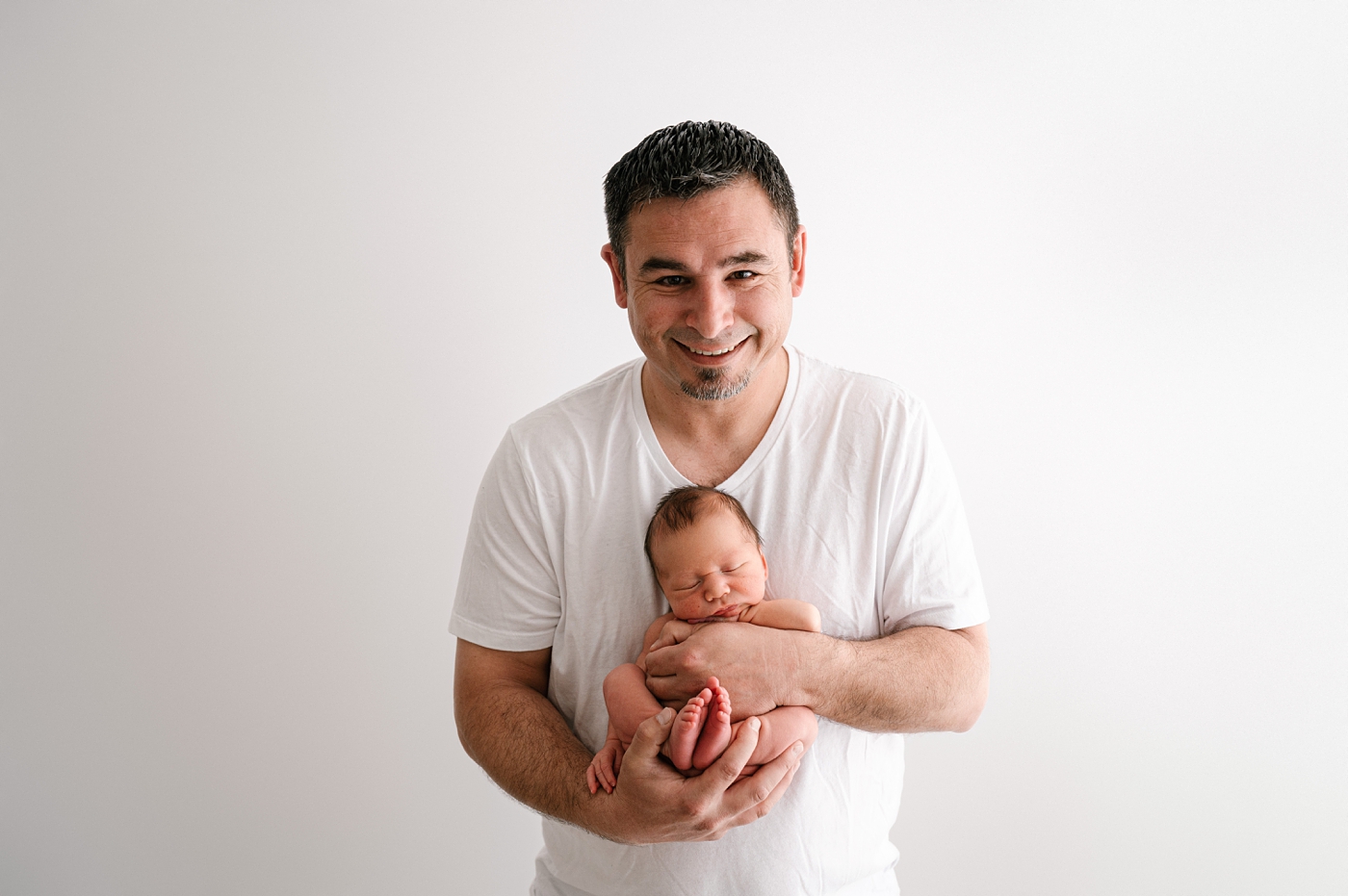 Dad proudly holds newborn son during Gig Harbor newborn session. Photo by Meg Newton Photography.