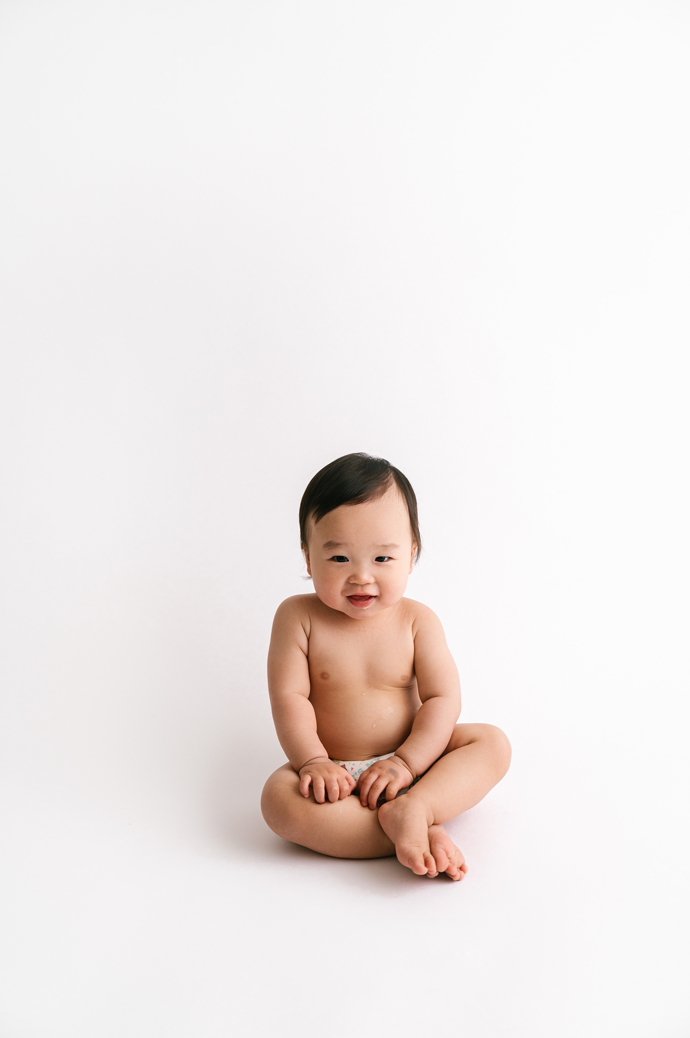 Baby boy sits criss-cross applesauce while being photographed. Photo by Meg Newton Photography.