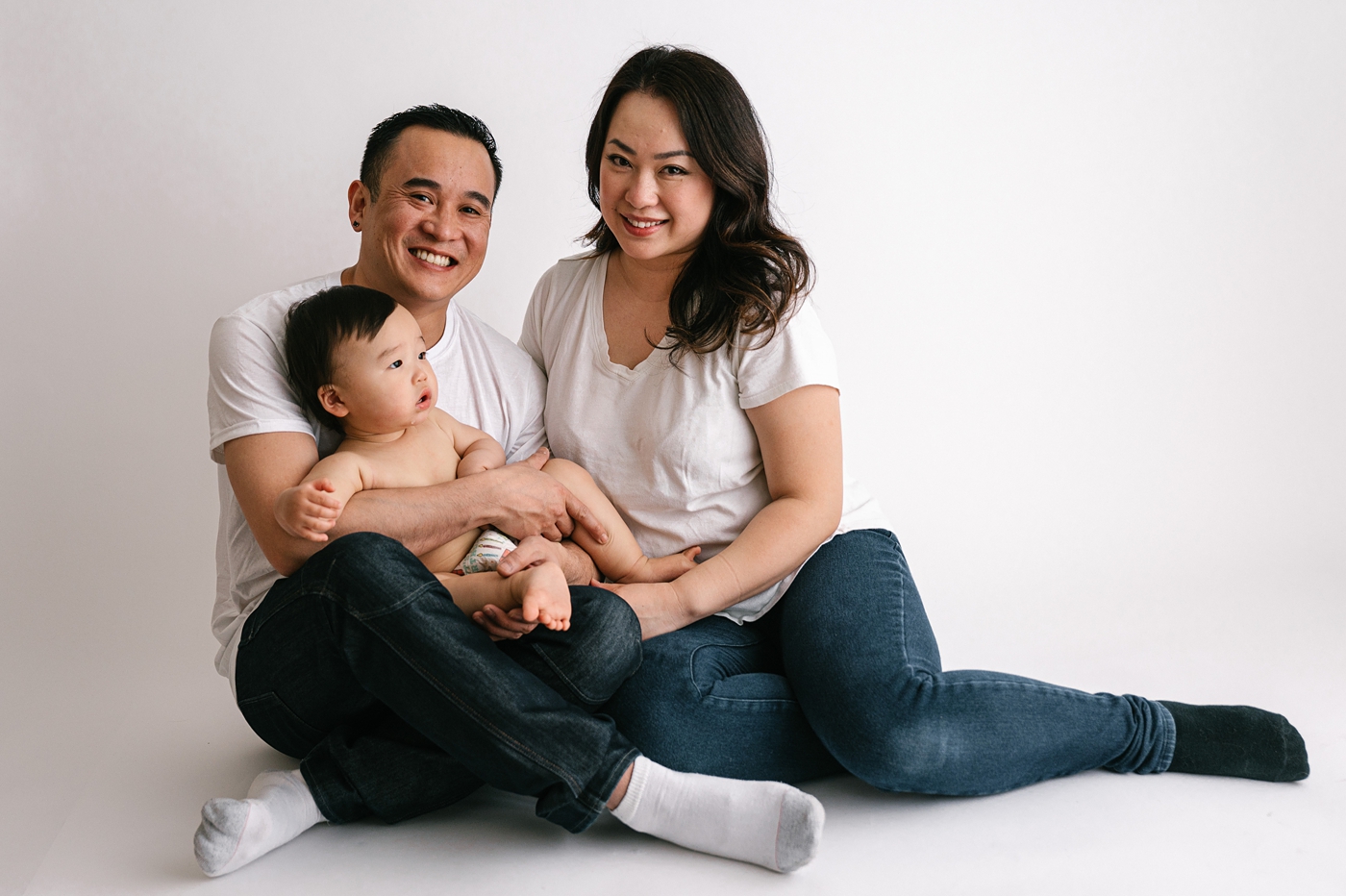 Family of three sits for photo during sitter session. Photo by Meg Newton Photography.