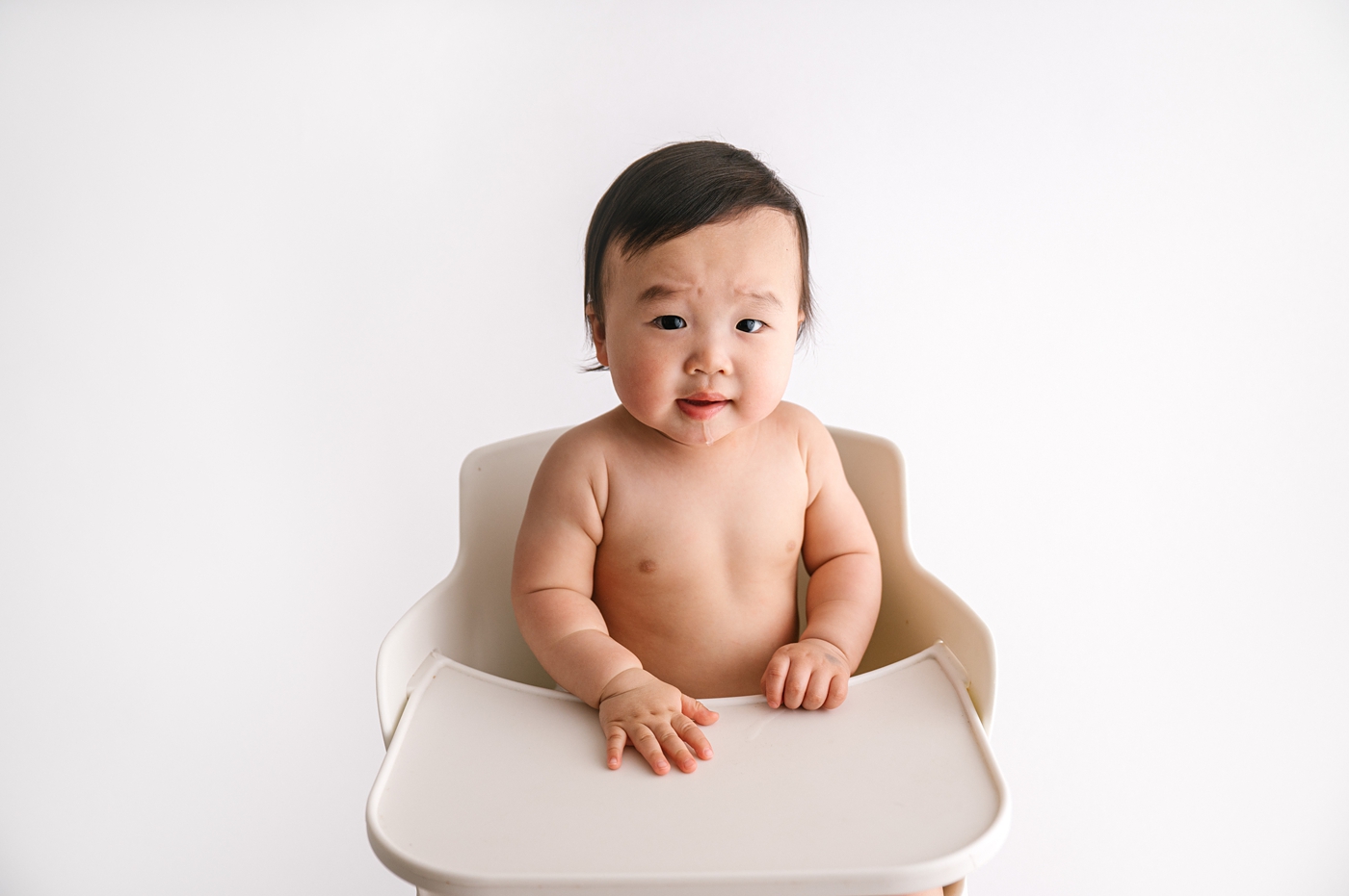 Baby boy sitting in white highchair. Photo by Meg Newton Photography.