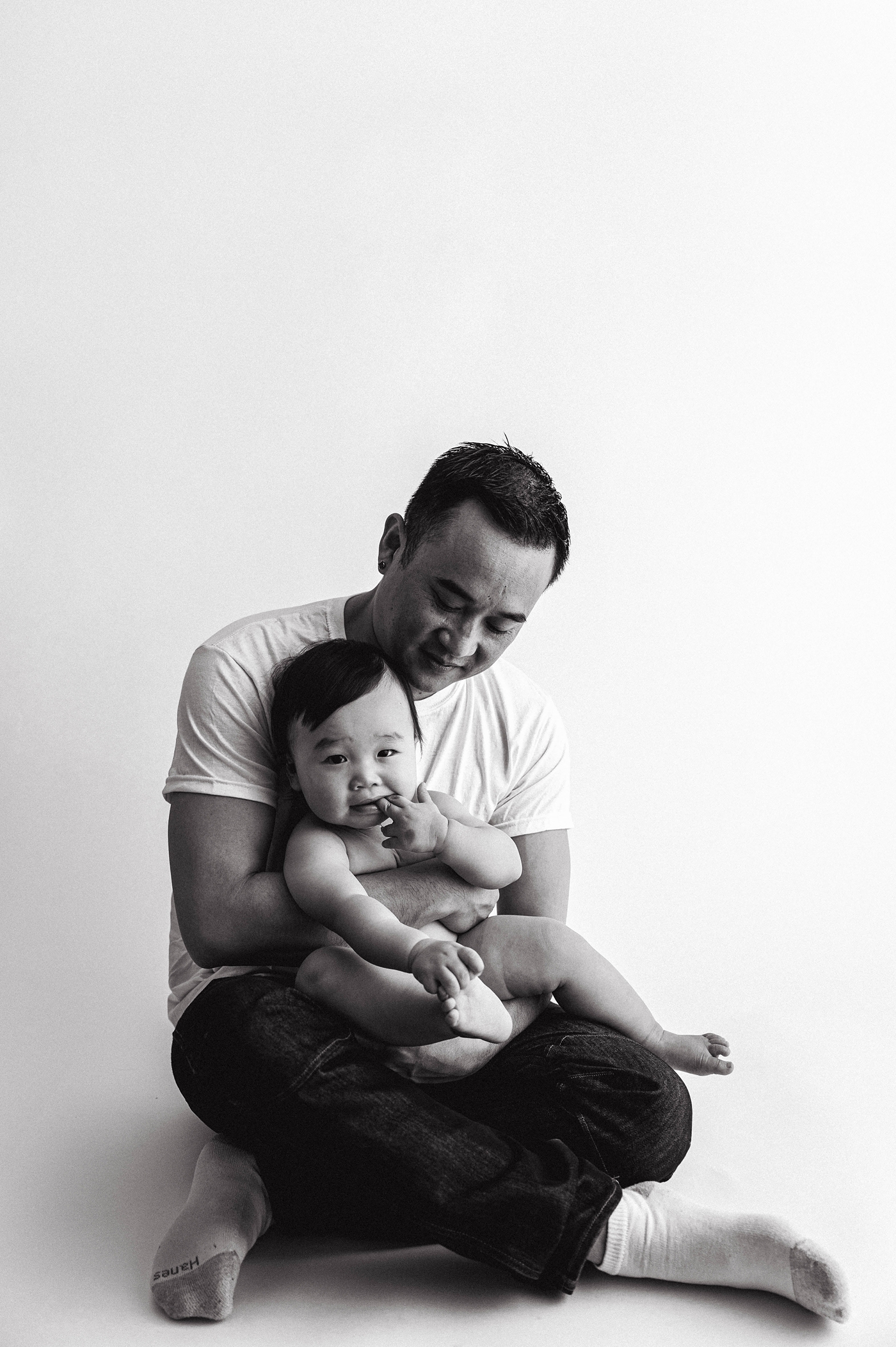 Little boy sits in dad's lap during sitter session. Photo by Meg Newton Photography.