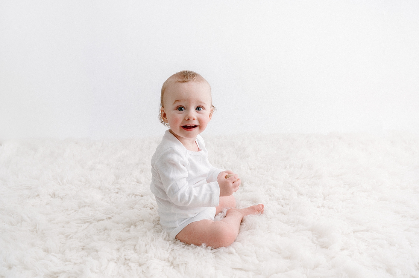 Baby boy sits in a white onesie during Seattle milestone session. Photo by Meg Newton Photography.