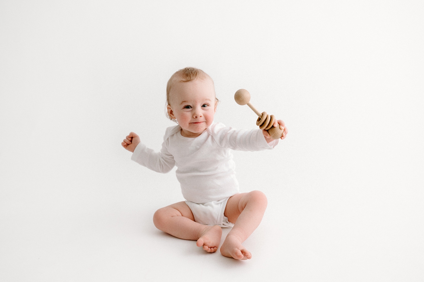 Baby boy plays with wooden rattle during Gig Harbor milestone session. Photo by Meg Newton Photography.