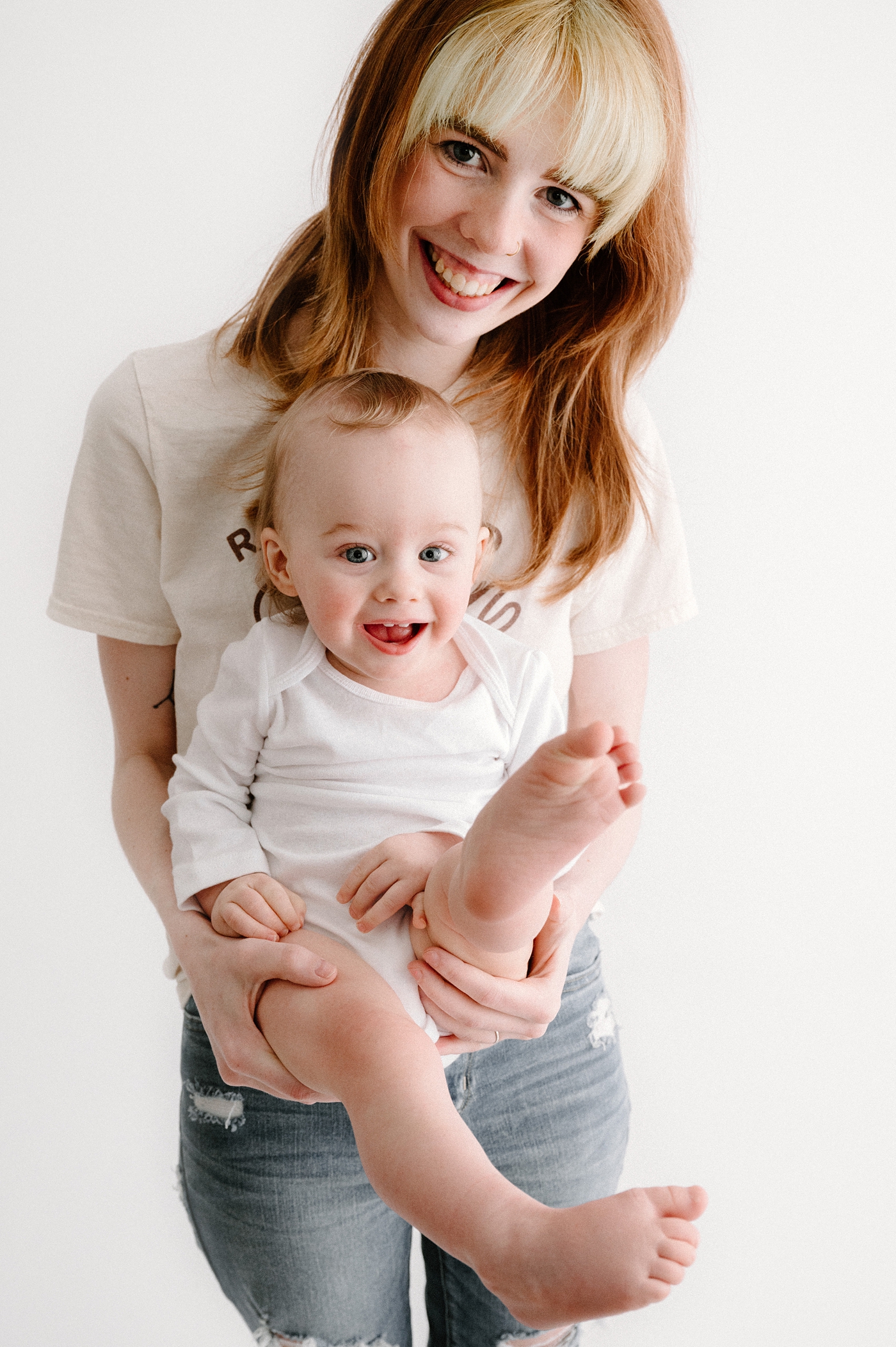 Mom with red and blonde hair holds son in her arms. Photo by Meg Newton Photography.