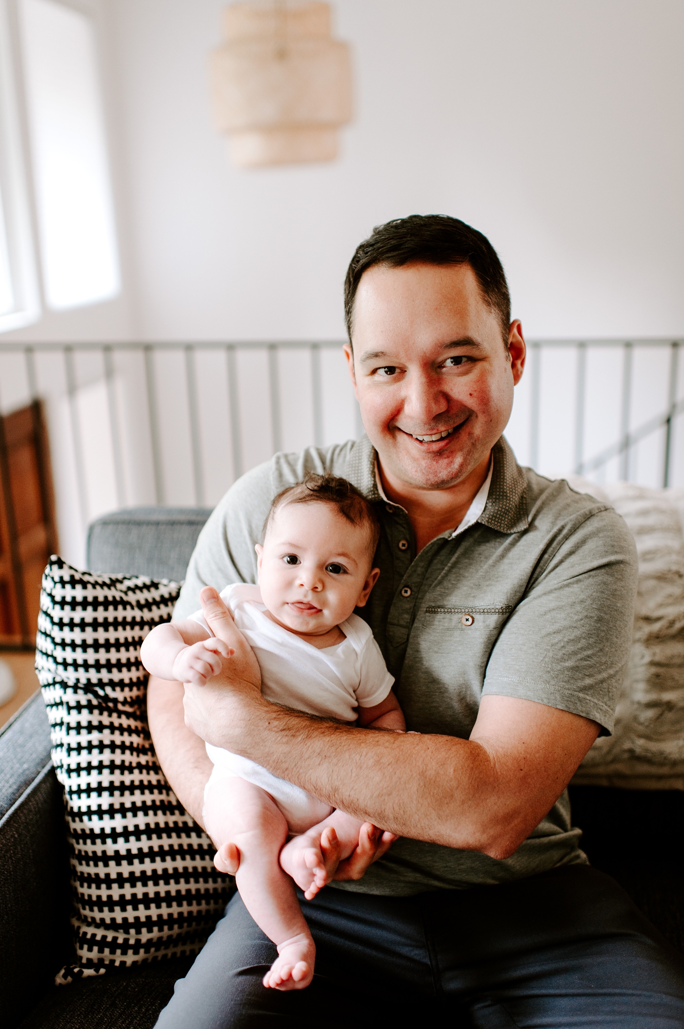 Dad holds son in his lap during Seattle newborn session. Photo by Meg Newton Photography.