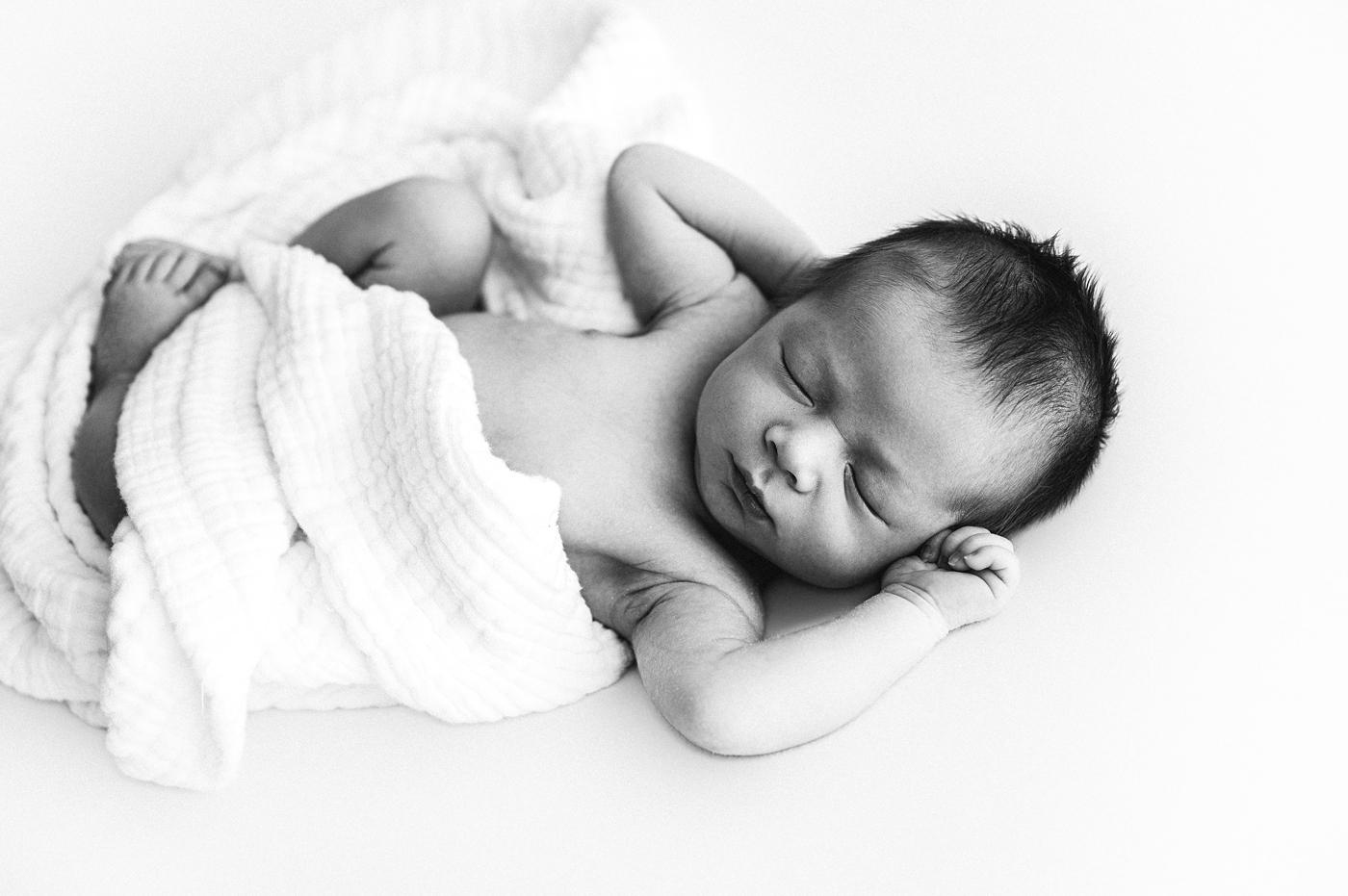 Newborn baby loosely wrapped in swaddle. Photo by Meg Newton Photography.