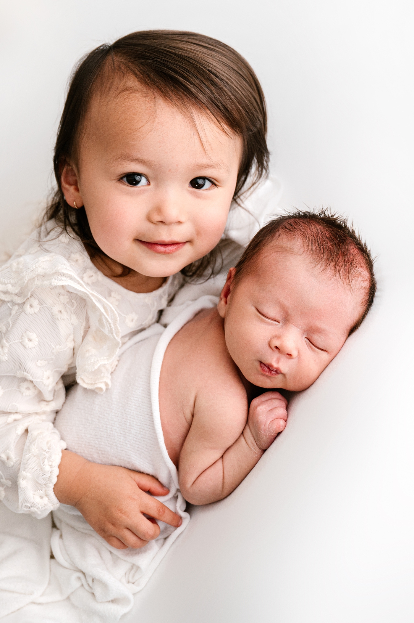 Older sister proudly holds her new little brother in Tacoma studio session. Photo by Meg Newton Photography.