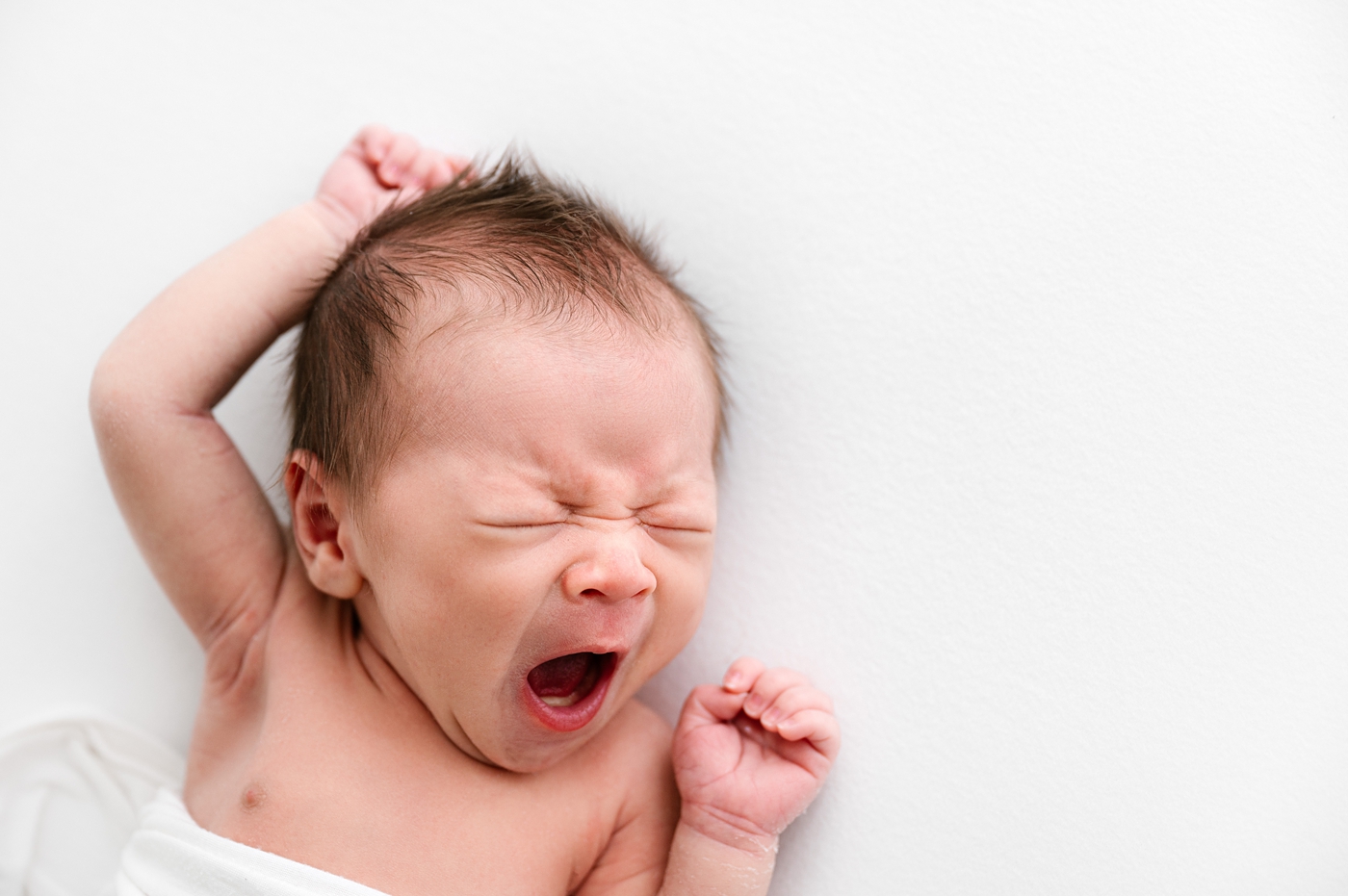 Baby boy yawns during newborn session. Photo by Meg Newton Photography.