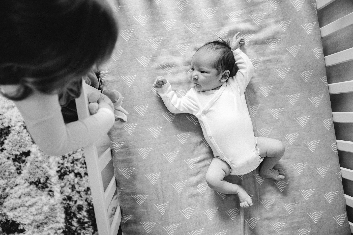 Big sister peers in on baby brother while he lays in his crib. Photo by Meg Newton Photography.