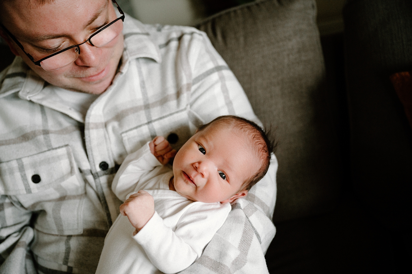 Alert baby boy is held in his dad's arms during in home newborn session. Photo by Meg Newton Photography.