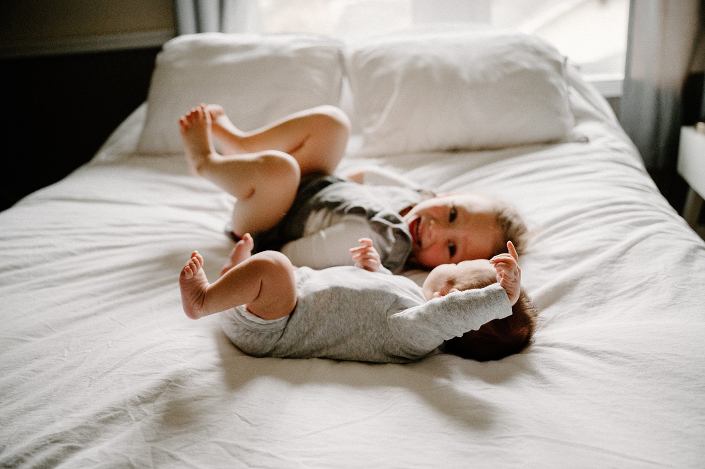Sister and new baby brother lay on bed during Olympia in home newborn session. Photo by Meg Newton Photography.