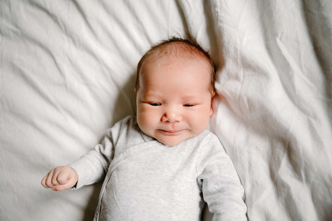 Newborn baby boy smiling during in home lifestyle newborn session in Olympia, WA. Photo by Meg Newton Photography.