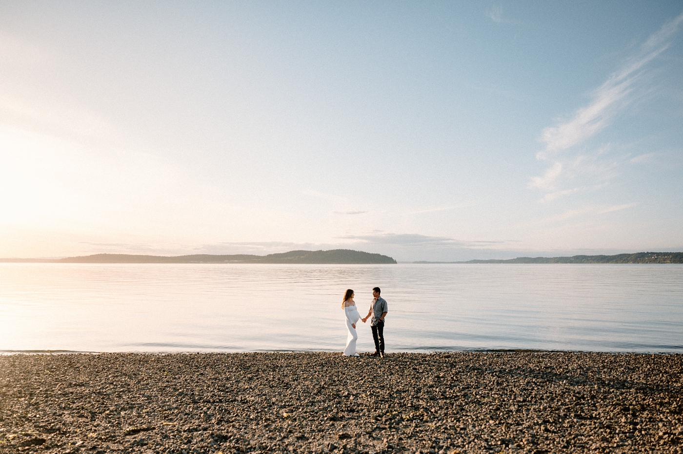 Pullback of expecting couple in front of Hood Canal. Image by PNW maternity photographer Meg Newton.