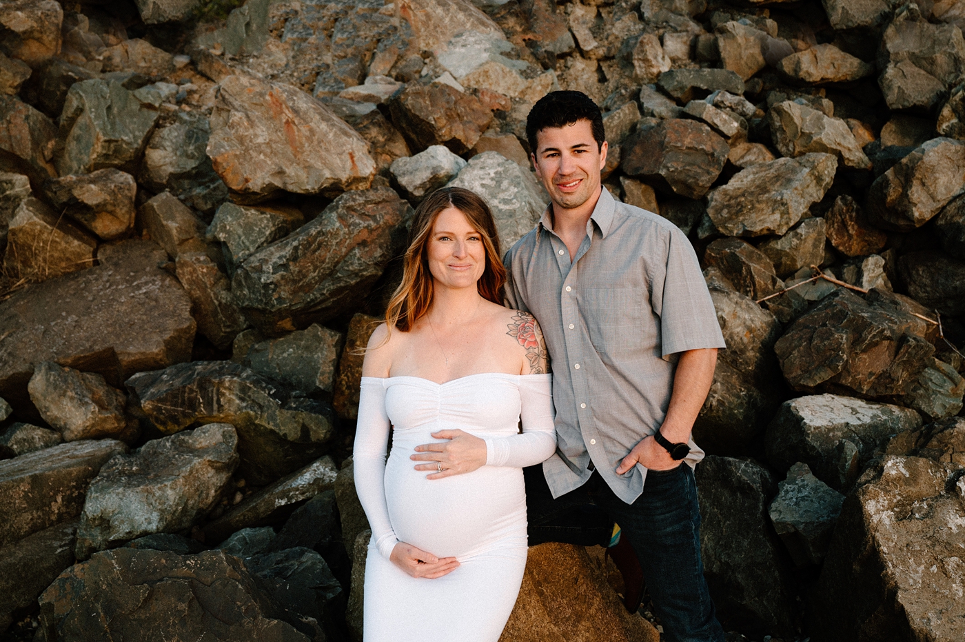 Mom & Dad stand in front of rock birm during maternity session. Image by PNW maternity photographer Meg Newton.