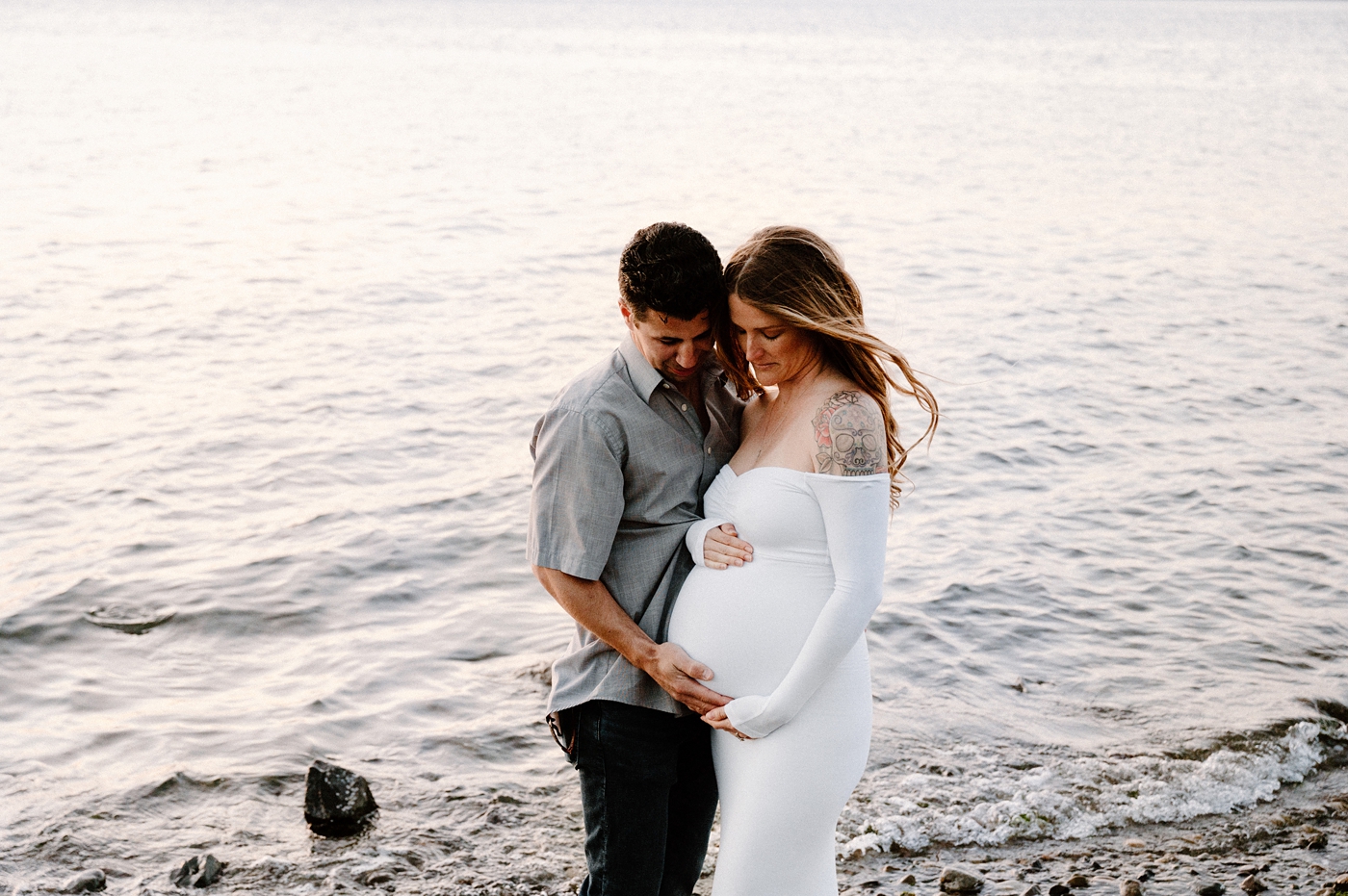Dad embraces mom's belly in front of Hood Canal. Image by PNW maternity photographer Meg Newton.