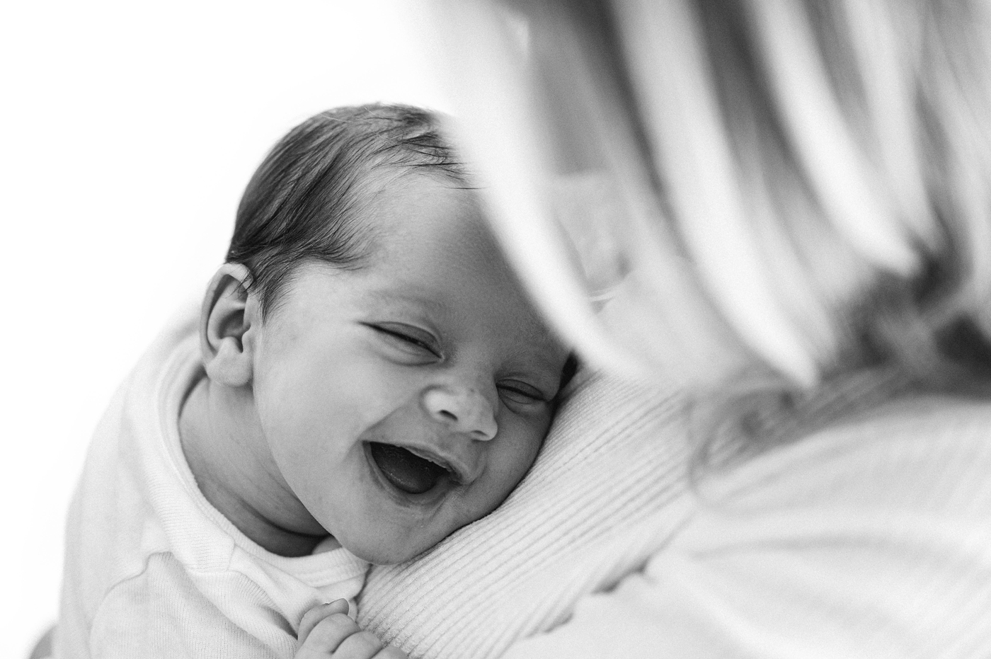 Baby girl smiles with joy in her mom's arms. Image by Meg Newton Photography.