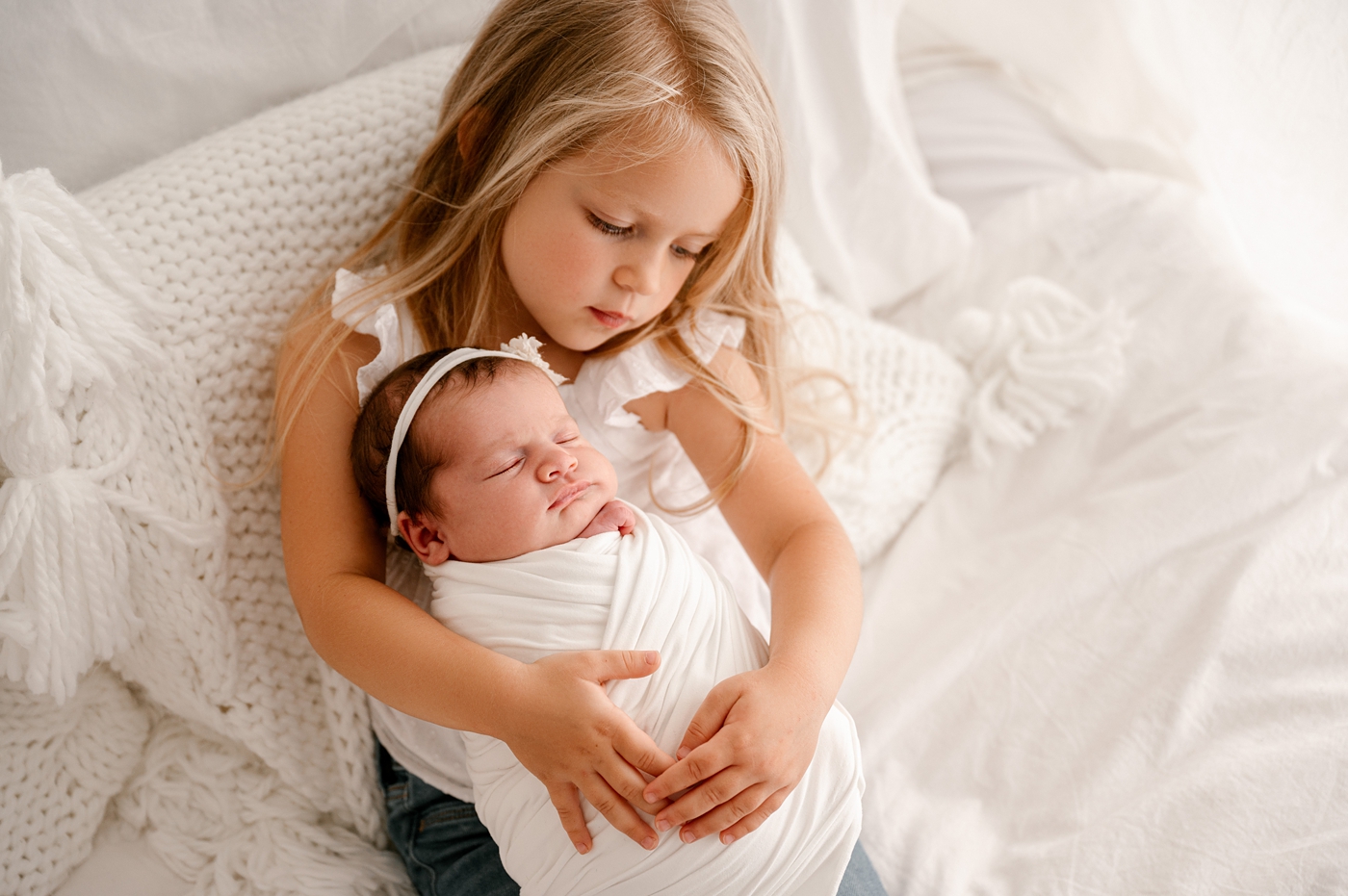 Big sister holds baby sister. Image by Meg Newton Photography.