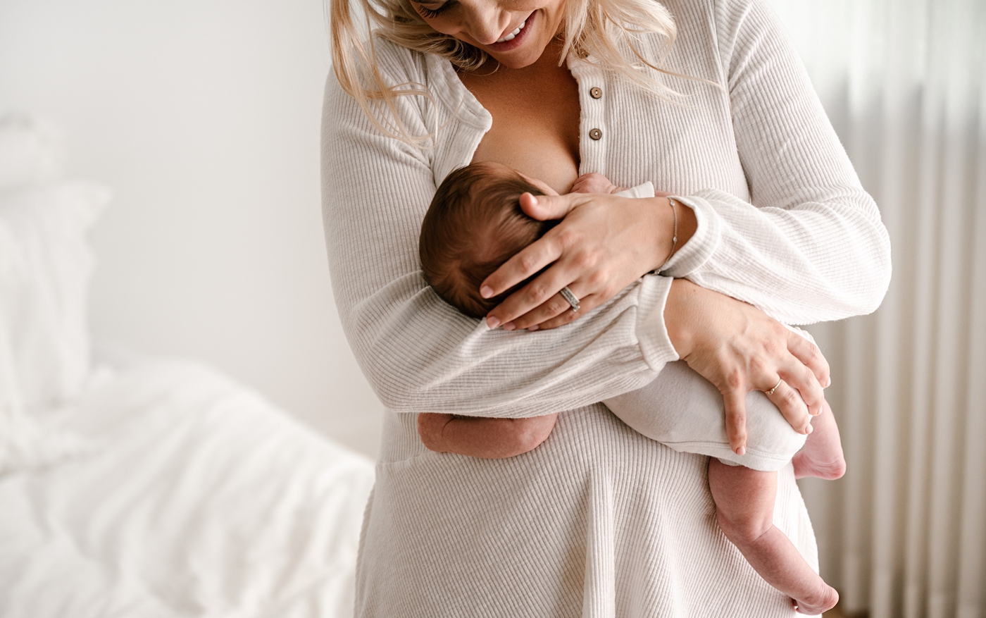 Mom tenderly holds daughter during lifestyle studio newborn session. Image by Meg Newton Photography.