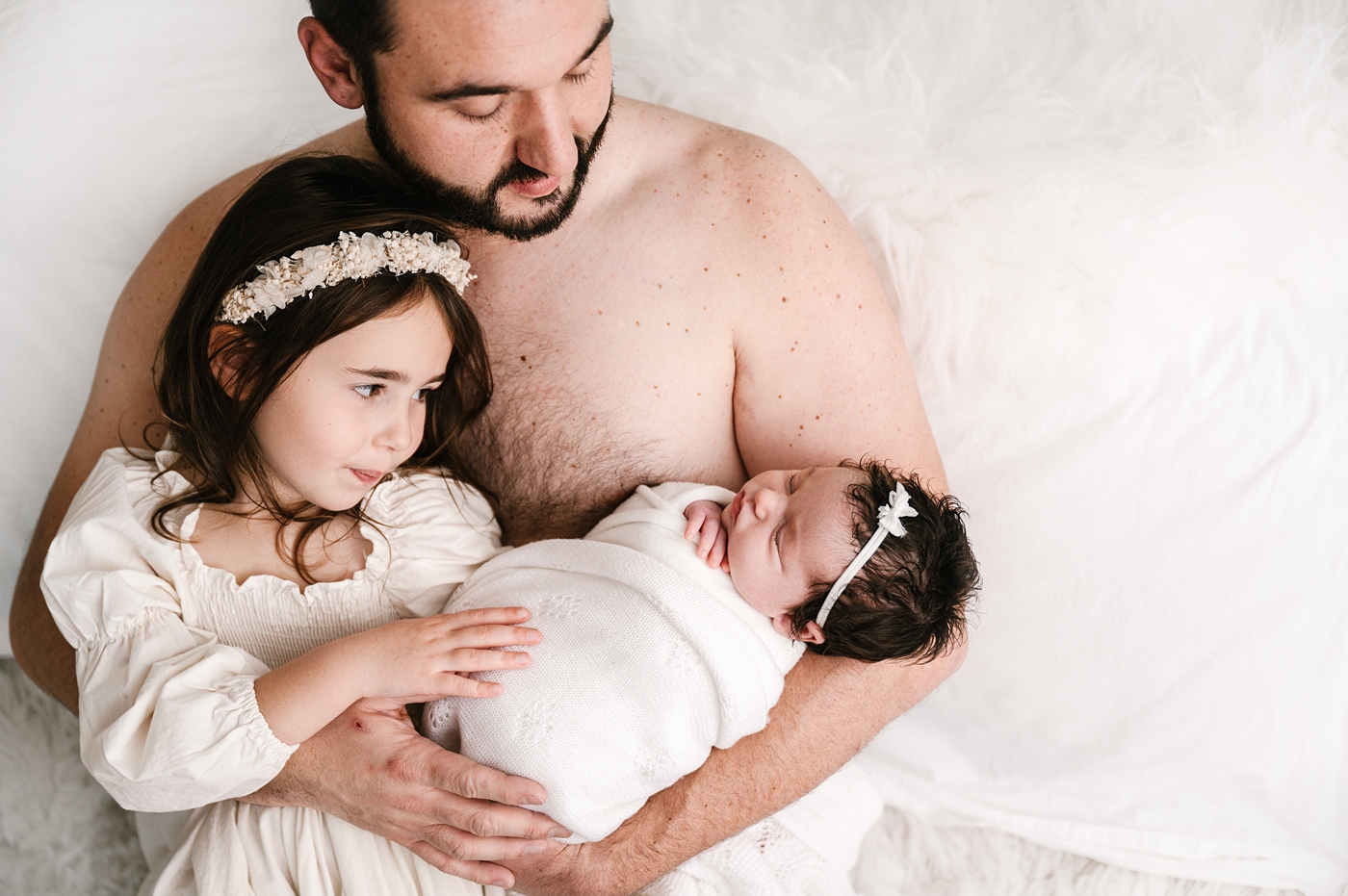 Dad holds his daughters during Tacoma newborn session. Image by Meg Newton Photography.