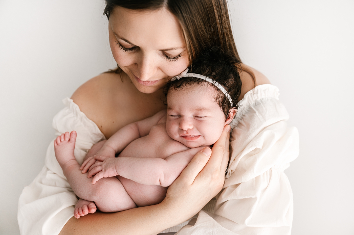 Mom holds her smiling newborn daughter. Image by Meg Newton Photography.