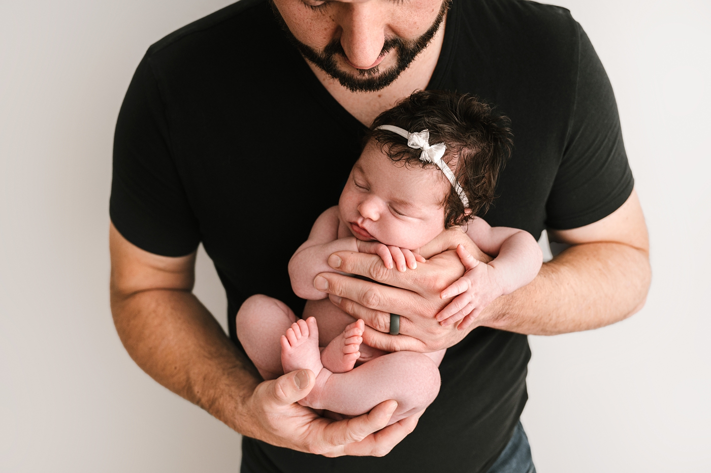 Dad holds newborn daughter during studio session. Image by Meg Newton Photography.