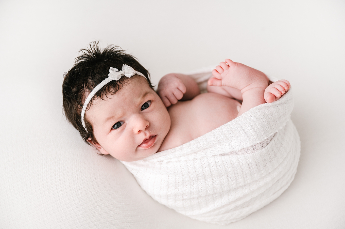 Baby girl looks right into camera during Tacoma newborn studio session. Image by Meg Newton Photography.