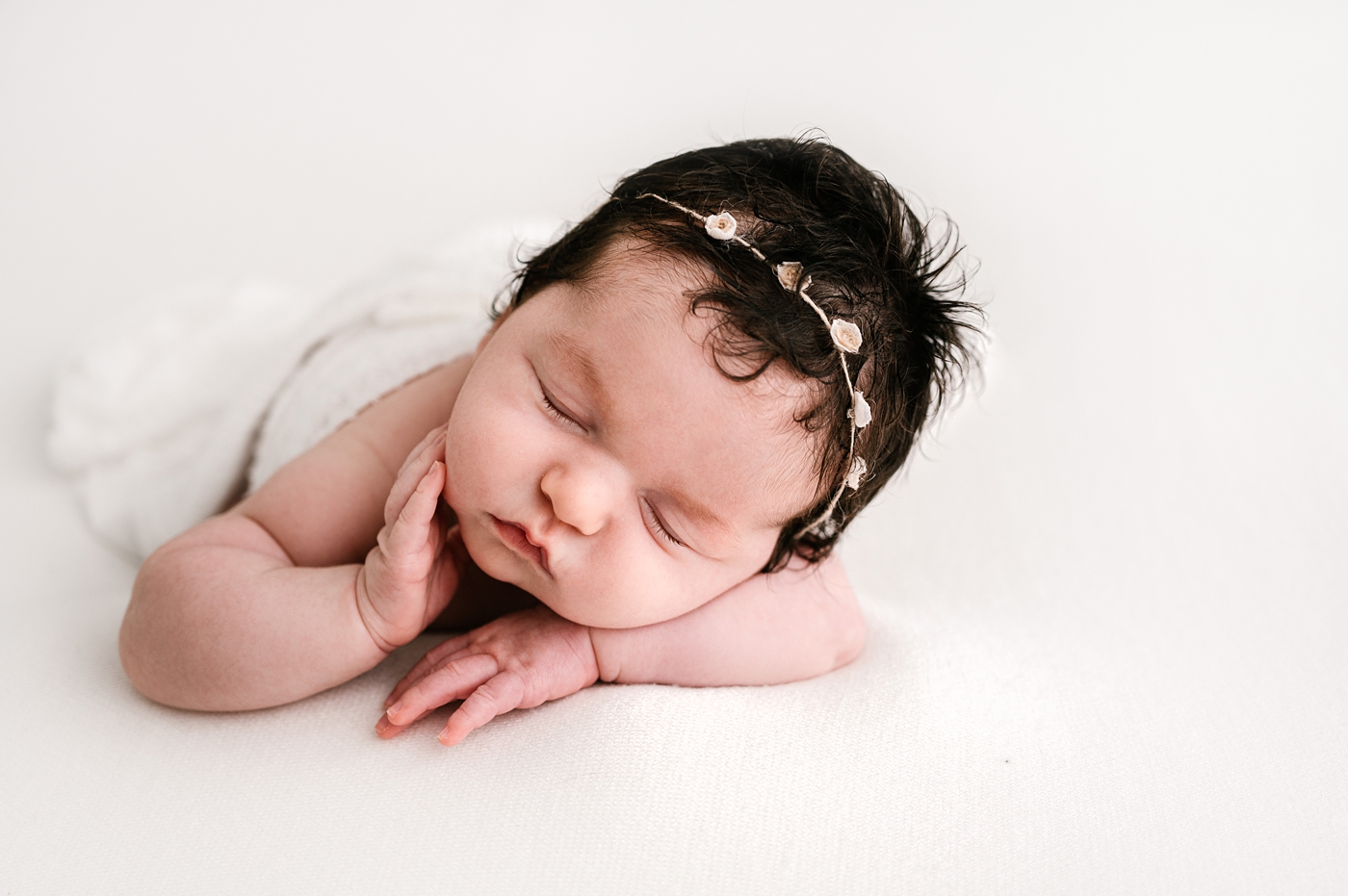Baby girl rests hand atop her face during her newborn session. Image by Meg Newton Photography.