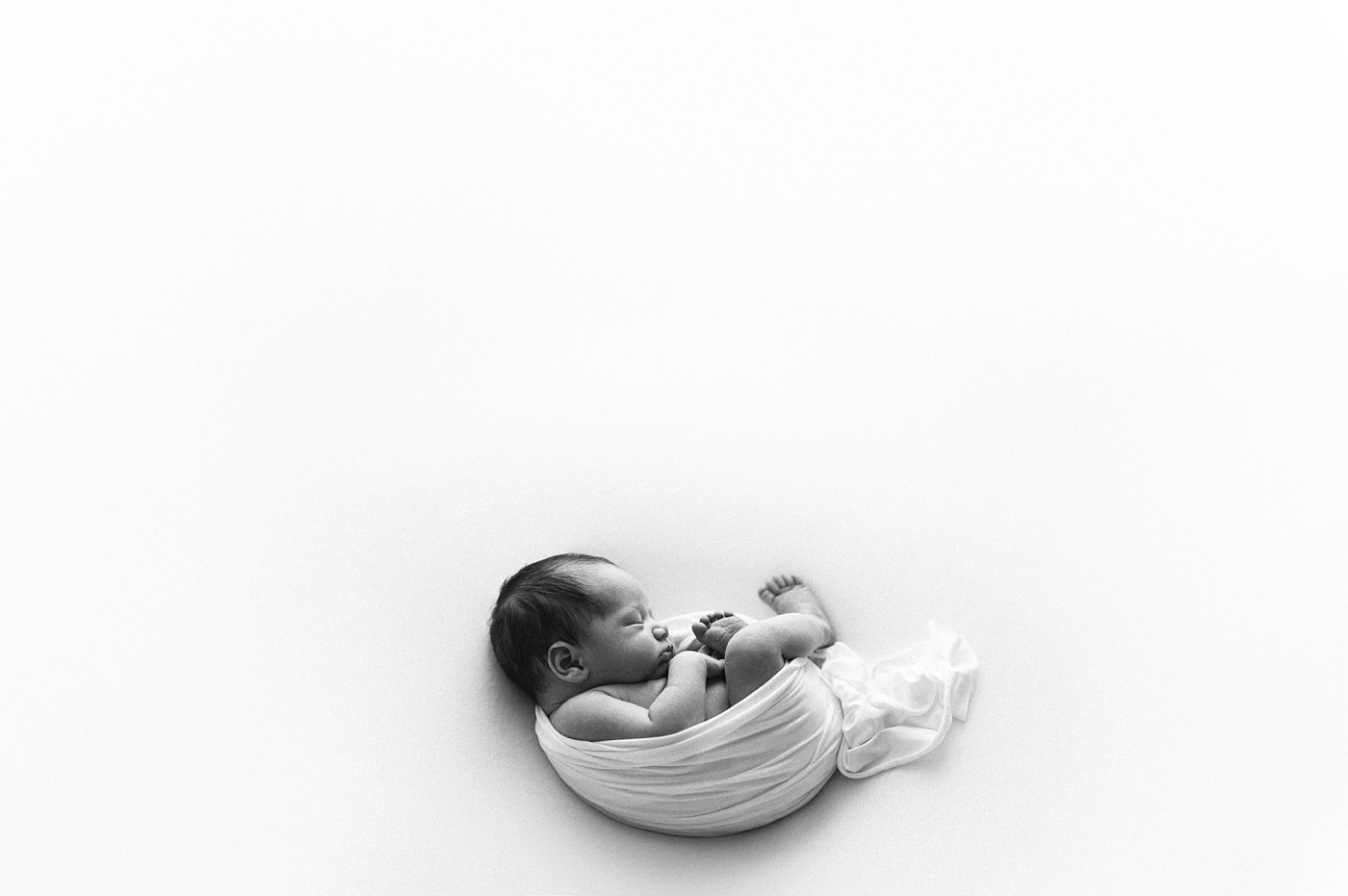 Baby swaddled in negative space. Photo by Meg Newton Photography.