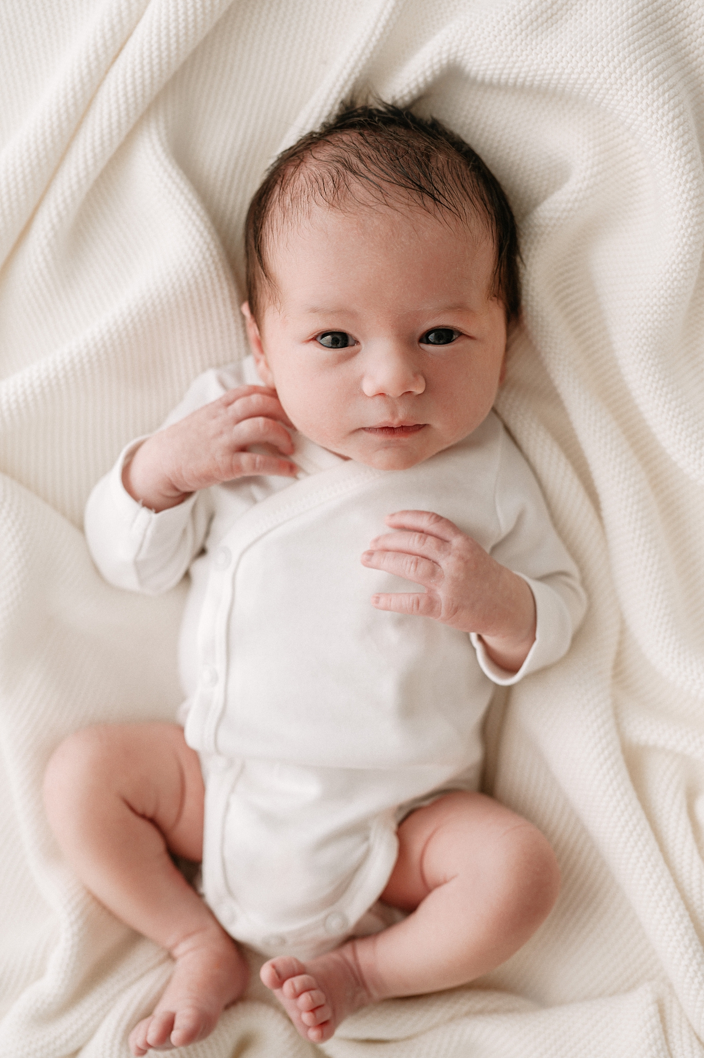 Baby boy stares bright eyed into camera while wearing simple onesie. Photo by Meg Newton Photography.