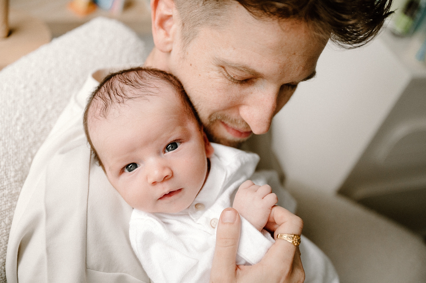 Baby boy stares wide eyed into camera while dad holds him. Photo by Meg Newton Photography.