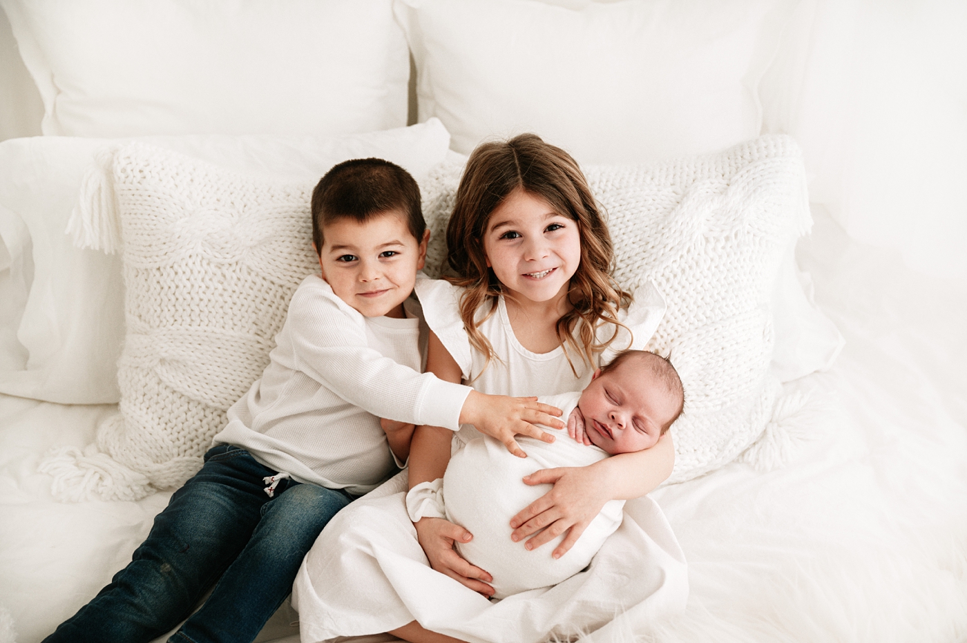 Brother and sister hold baby brother during Tacoma Studio newborn session. Photo by Meg Newton Photography.