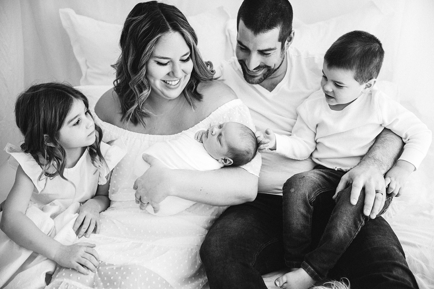 Family of five lovingly looks down at their newest baby brother. Photo by Meg Newton Photography.
