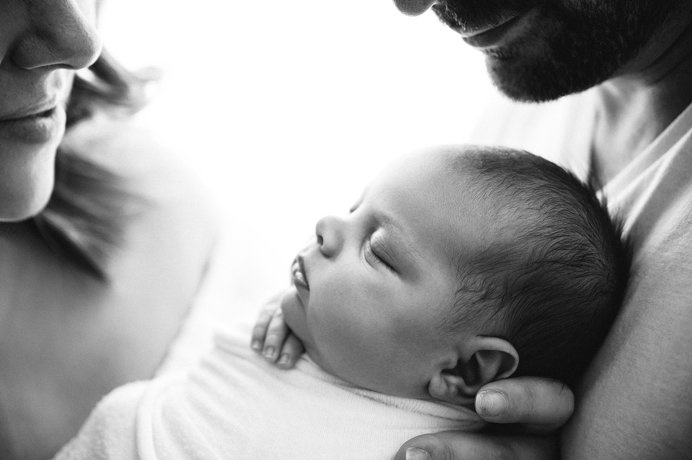 Close up of baby boy held between his parents. Photo by Meg Newton Photography.