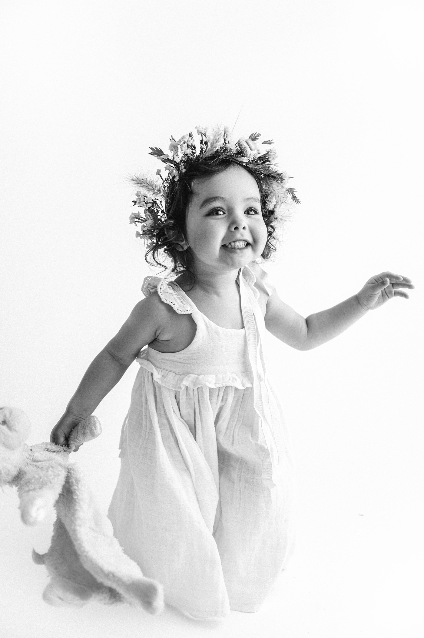Baby girl smiles and jumps during her milestone session. Photo by Meg Newton Photography.
